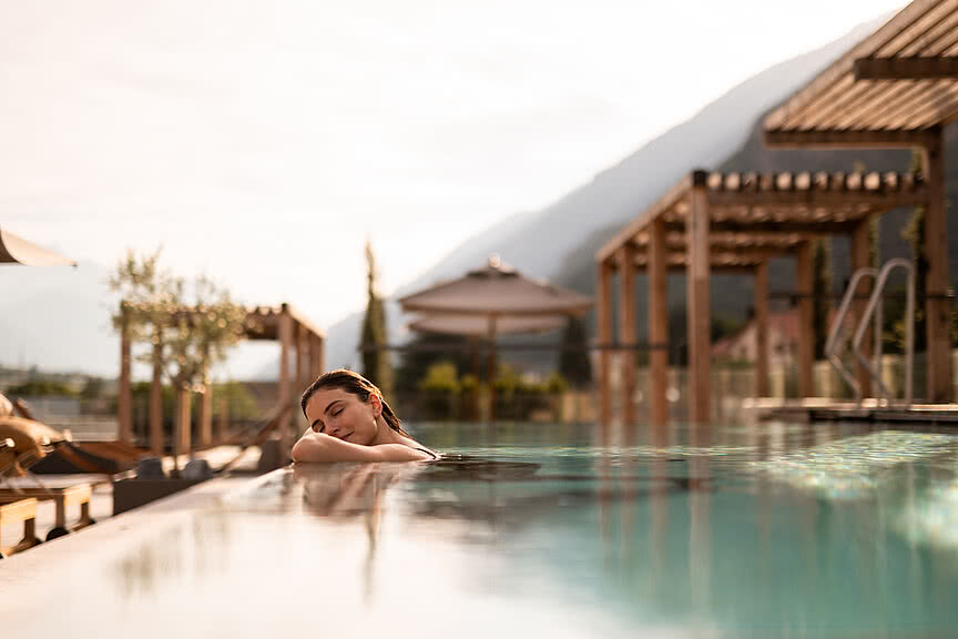 Junge Frau beim Entspannen im Wellnessurlaub im Infinity-Rooftop-Pool des Sonnen Resorts Südtirol