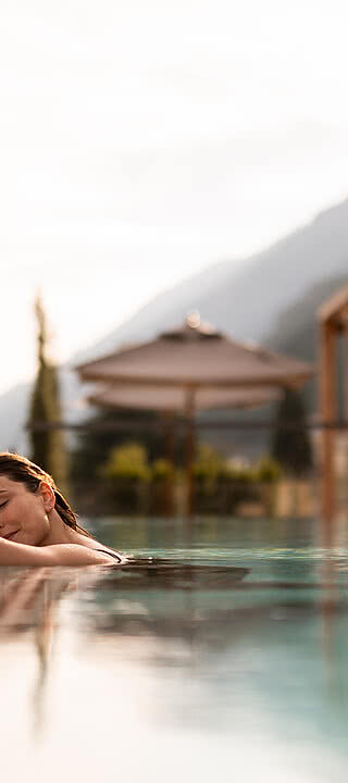 Junge Frau beim Entspannen im Wellnessurlaub im Infinity-Rooftop-Pool des Sonnen Resorts Südtirol