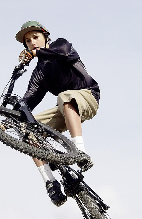 Mit einem entschlossenen Gesichtsausdruck vollbringt der Teenager einen luftigen Trick auf seinem Mountainbike in freier Natur.