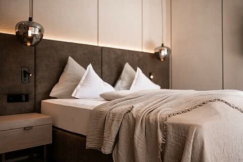 Bett in einer modernen Suite im Hotel Sonnen Resort in Naturns Südtirol