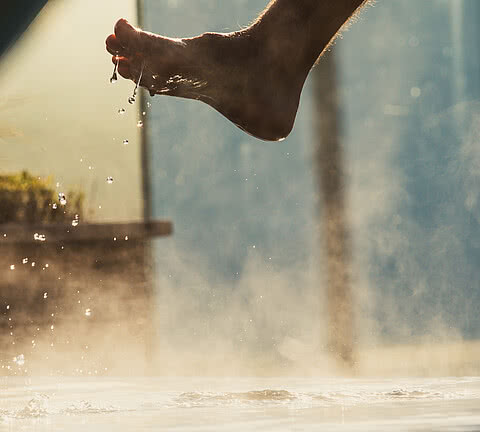 Fuß taucht in warmen Thermalwasserpool im Wellnesshotel Sonnen Resort in Südtirol ein