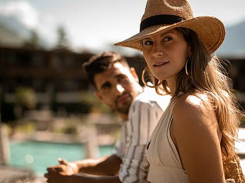 Ein Paar genießt die Sonne am Pool im Sonnenresort Wellnesshotel Südtirol.