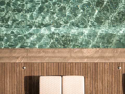 Sonnendeck mit Liegen am glasklaren Pool im Sonnenresort Wellnesshotel in Südtirol.