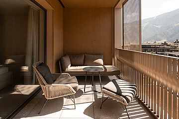 Ein gemütlicher Balkon mit bequemer Sitzgelegenheit im Hotel Sonnen Resort Naturns