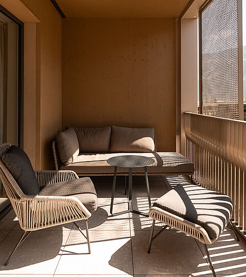 Ein gemütlicher Balkon mit bequemer Sitzgelegenheit im Hotel Sonnen Resort Naturns